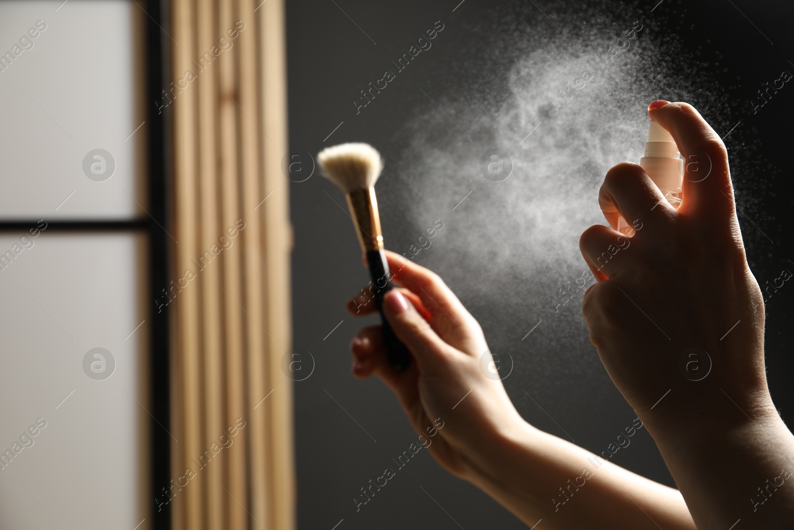 Photo of Woman cleaning makeup brush with spray indoors, closeup. Space for text