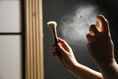 Photo of Woman cleaning makeup brush with spray indoors, closeup. Space for text