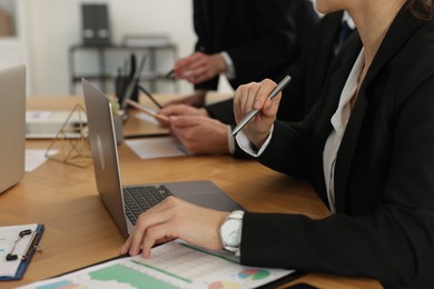 Photo of Coworkers working together at wooden table in office, closeup