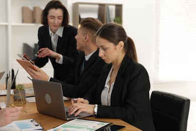 Coworkers working together at wooden table in office