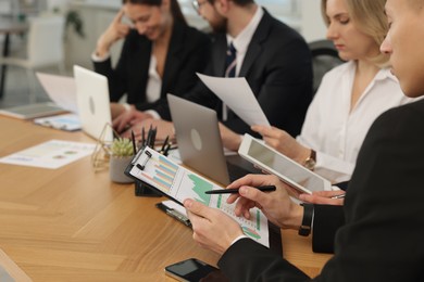 Photo of Coworkers working together at wooden table in office, selective focus