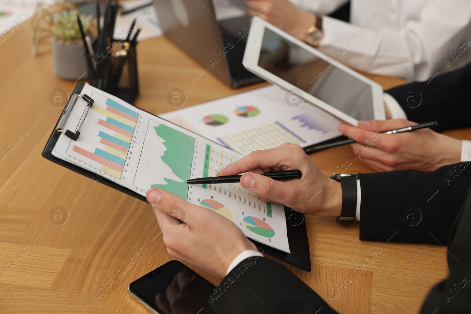 Photo of Coworkers working together at wooden table in office, closeup