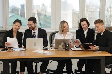 Photo of Coworkers working together at wooden table in office