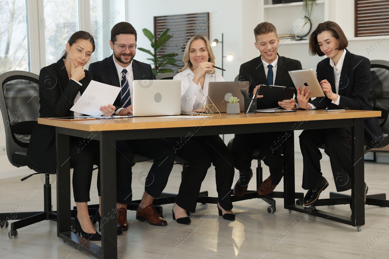 Photo of Coworkers working together at wooden table in office