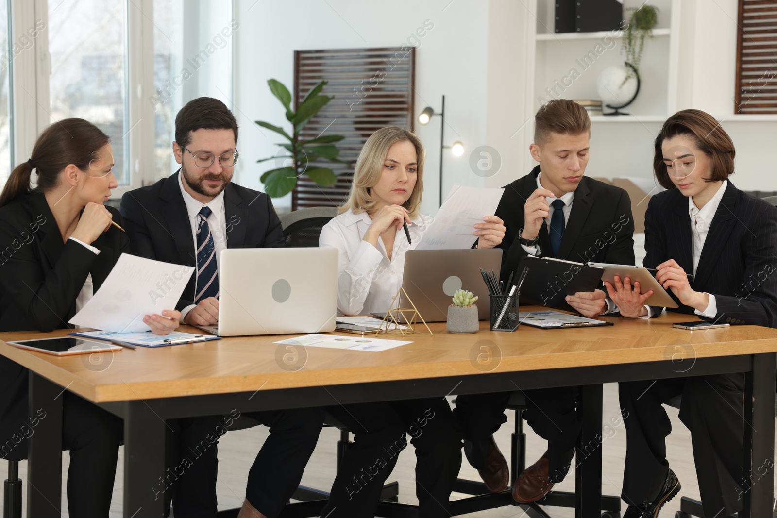 Photo of Coworkers working together at wooden table in office