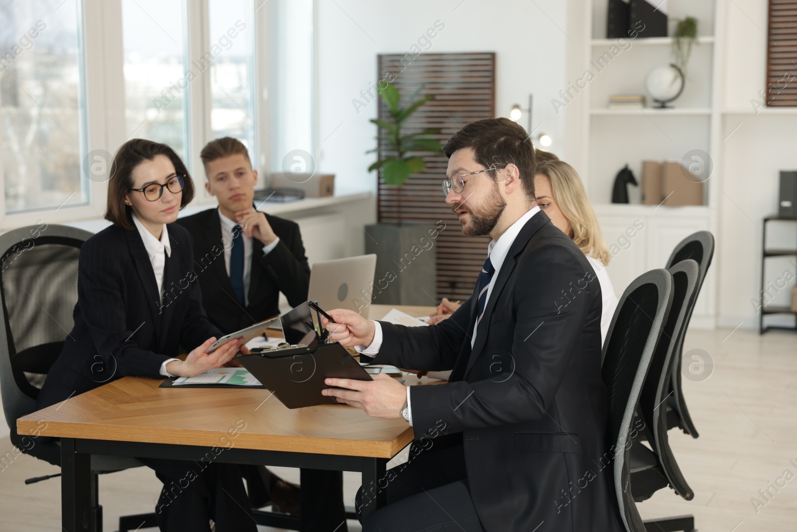 Photo of Coworkers working together at wooden table in office