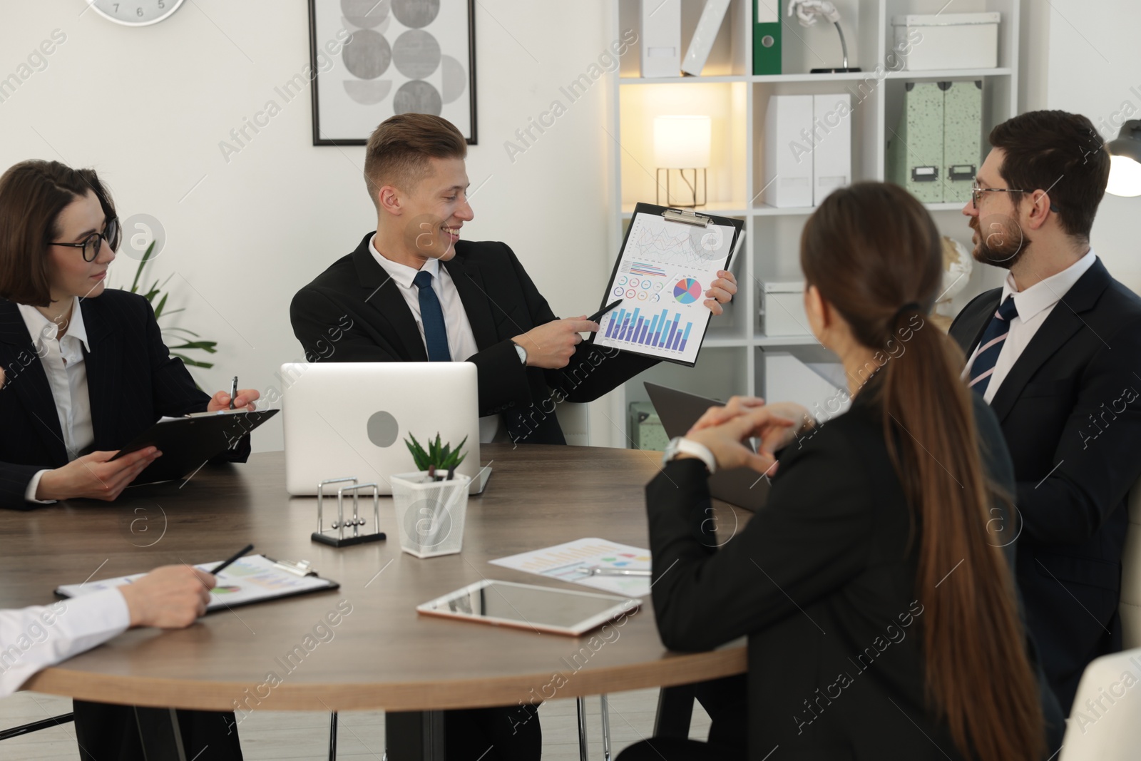 Photo of Coworkers working together at wooden table in office