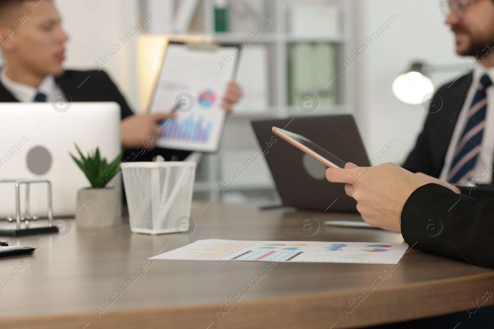 Photo of Coworkers working together at wooden table in office, selective focus