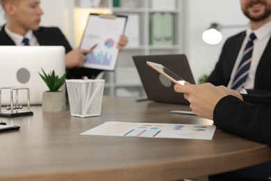 Photo of Coworkers working together at wooden table in office, selective focus