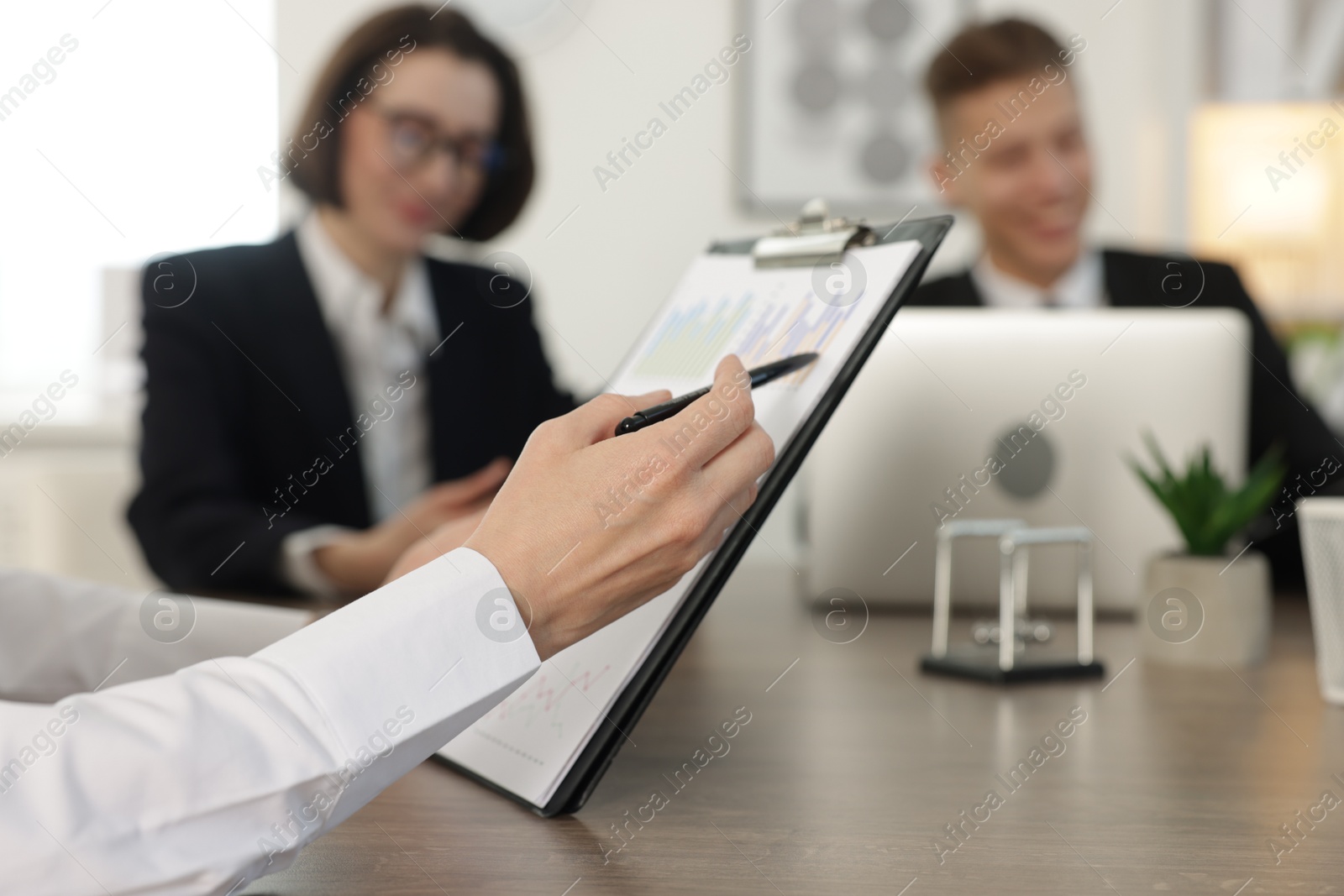 Photo of Coworkers working together at wooden table in office, selective focus