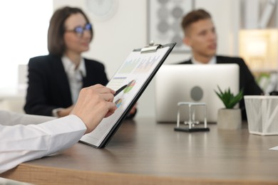 Photo of Coworkers working together at wooden table in office, selective focus