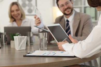 Coworkers working together at wooden table in office, selective focus