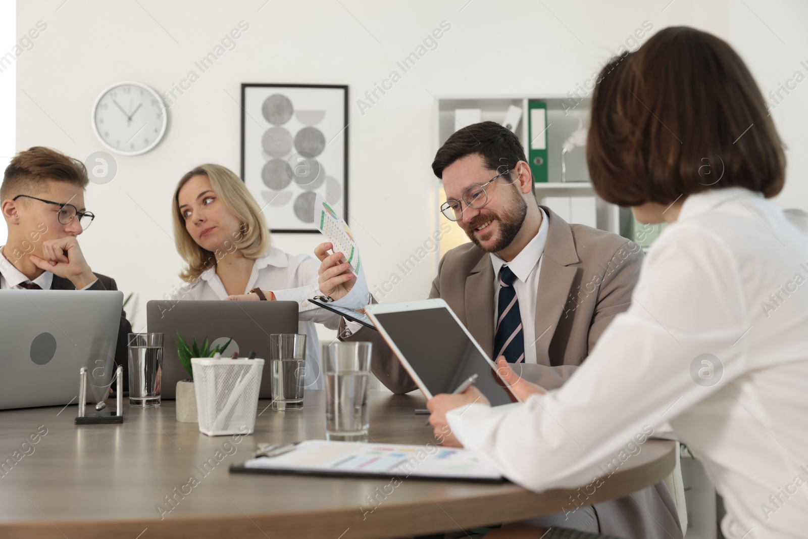 Photo of Coworkers working together at wooden table in office