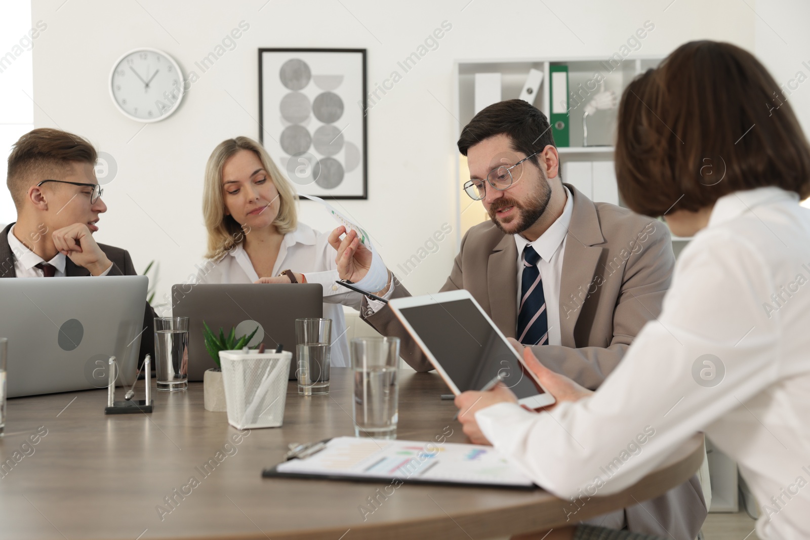 Photo of Coworkers working together at wooden table in office