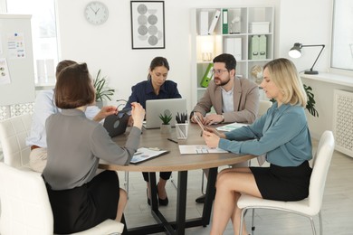 Photo of Coworkers working together at wooden table in office