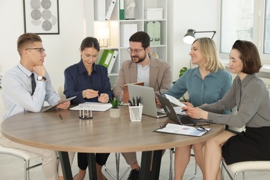 Coworkers working together at wooden table in office