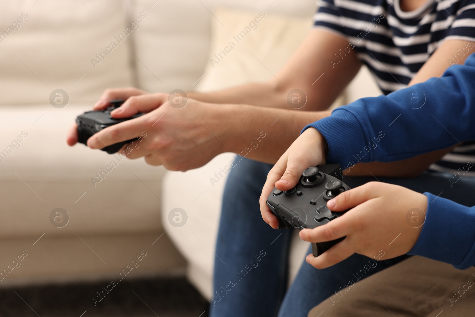 Photo of Father and his son playing video games on sofa indoors, closeup