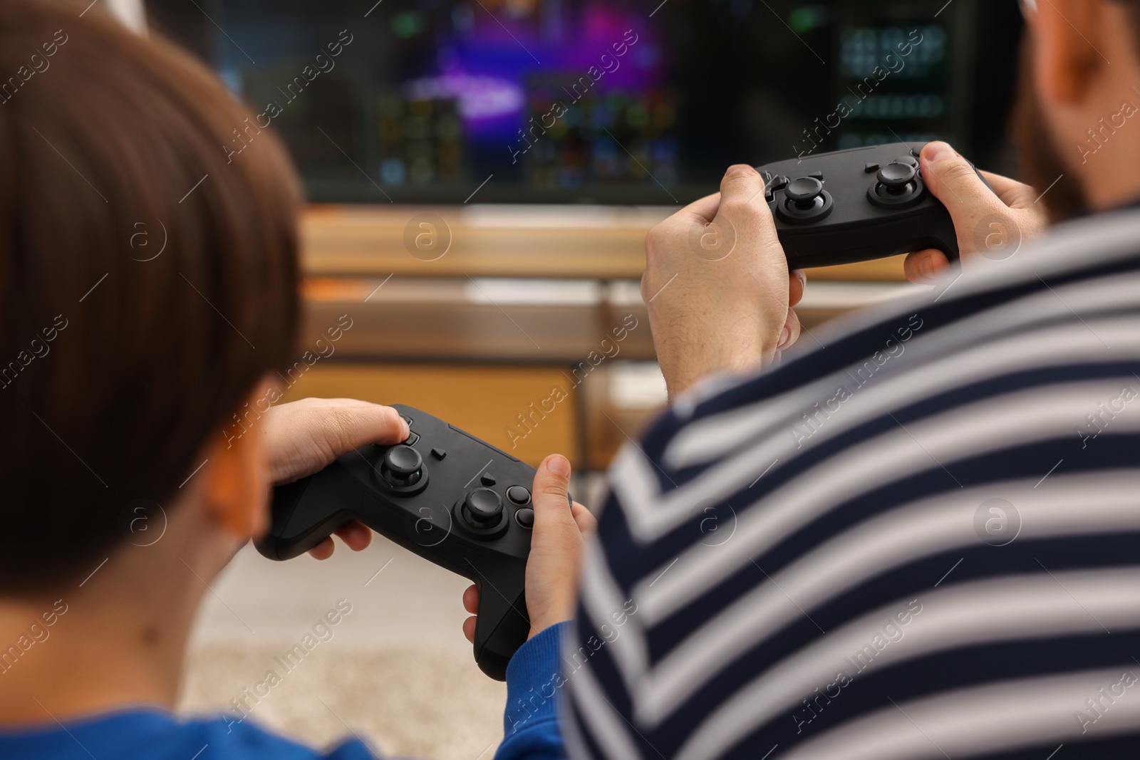 Photo of Father and his son playing video games at home, closeup