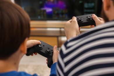 Photo of Father and his son playing video games at home, closeup