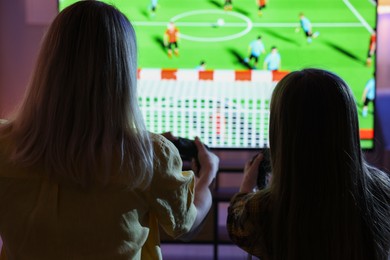 Photo of Mother and her daughter playing video game at home, back view