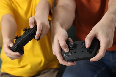 Photo of Father and his son playing video games at home, closeup