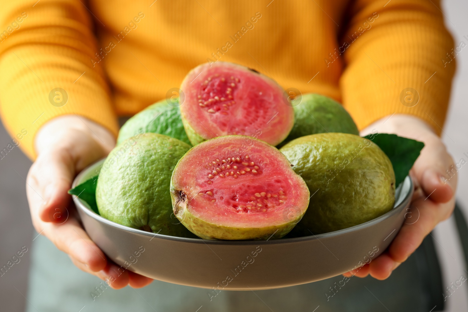 Photo of Woman with bowl of fresh guava fruits, closeup