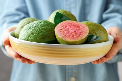 Photo of Woman with bowl of fresh guava fruits, closeup