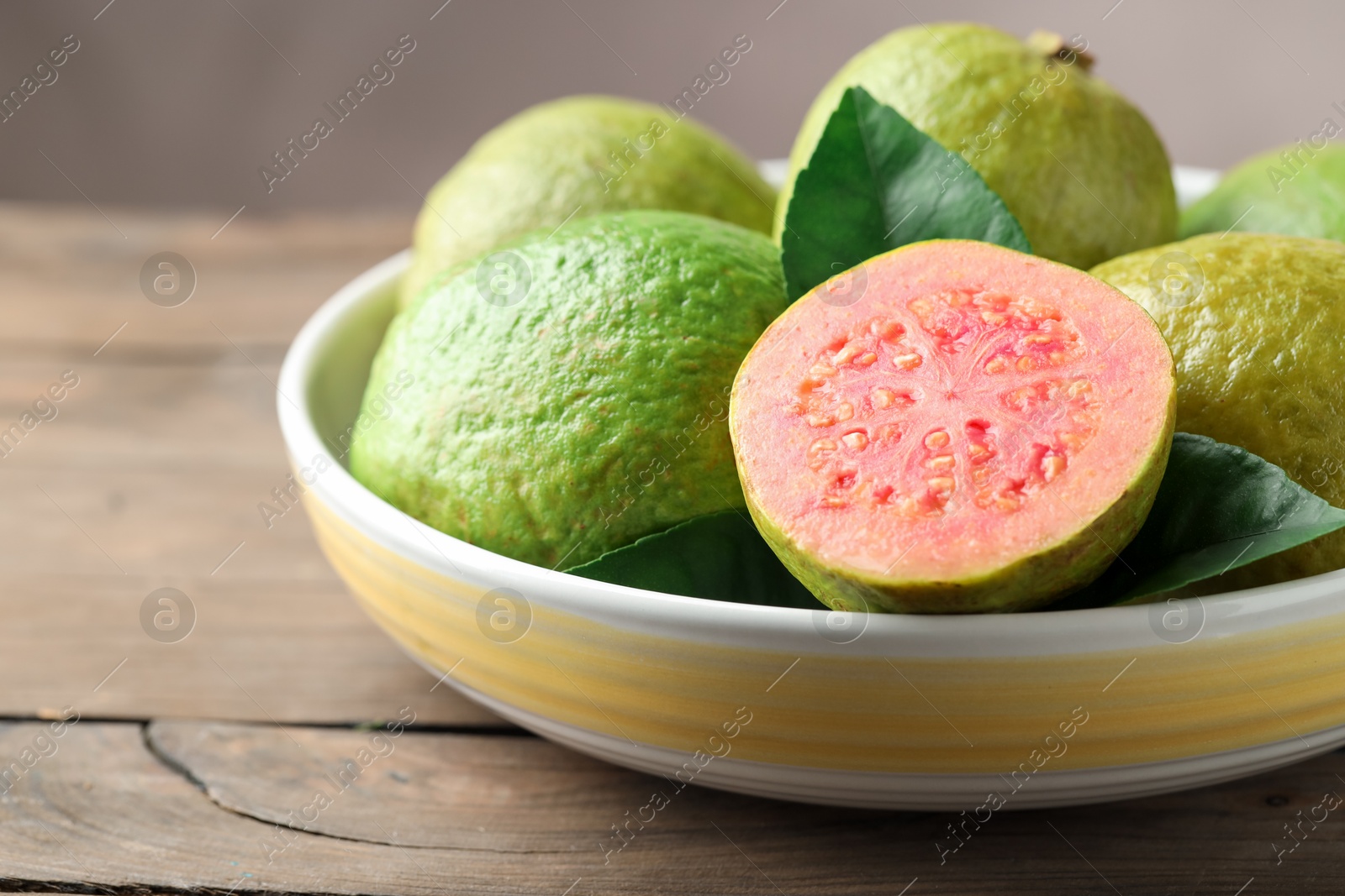 Photo of Fresh guava fruits in bowl on wooden table, closeup