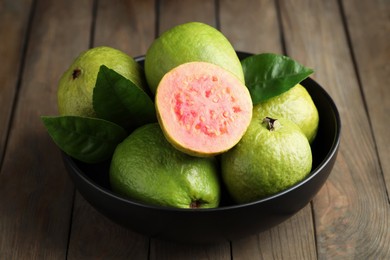 Photo of Fresh guava fruits in bowl on wooden table, closeup