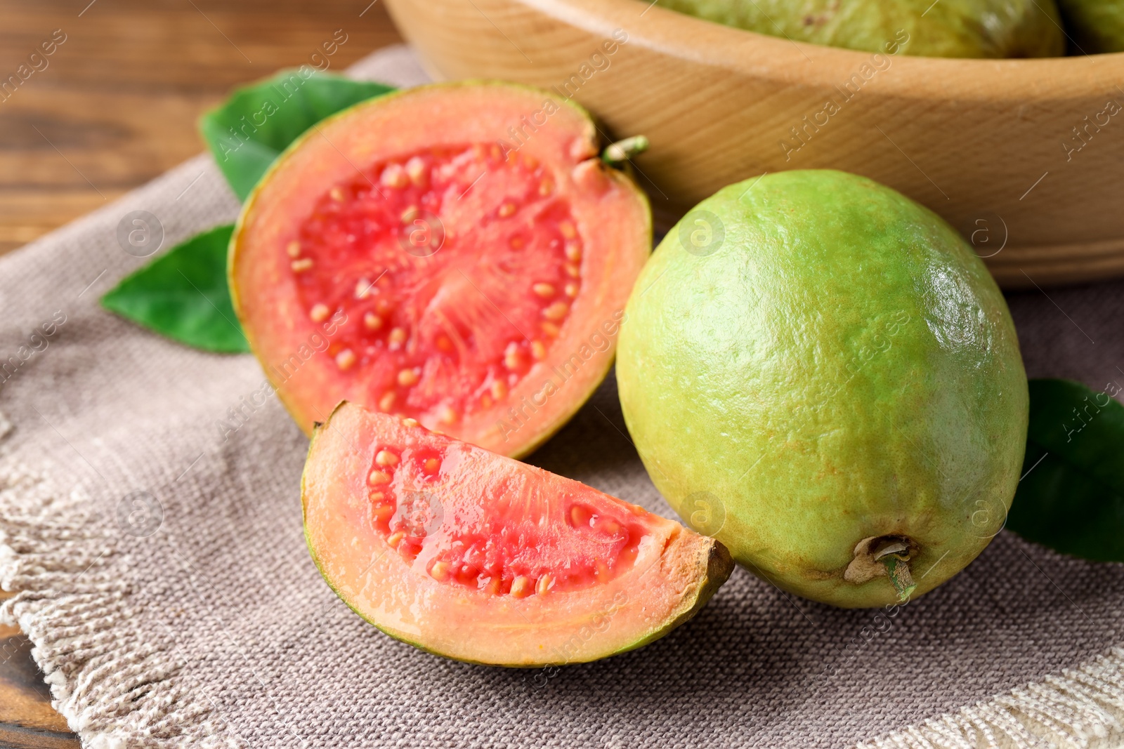 Photo of Fresh cut and whole guava fruits on wooden table, closeup