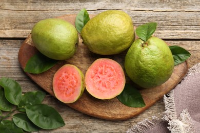 Fresh whole and cut guava fruits on wooden table, flat lay