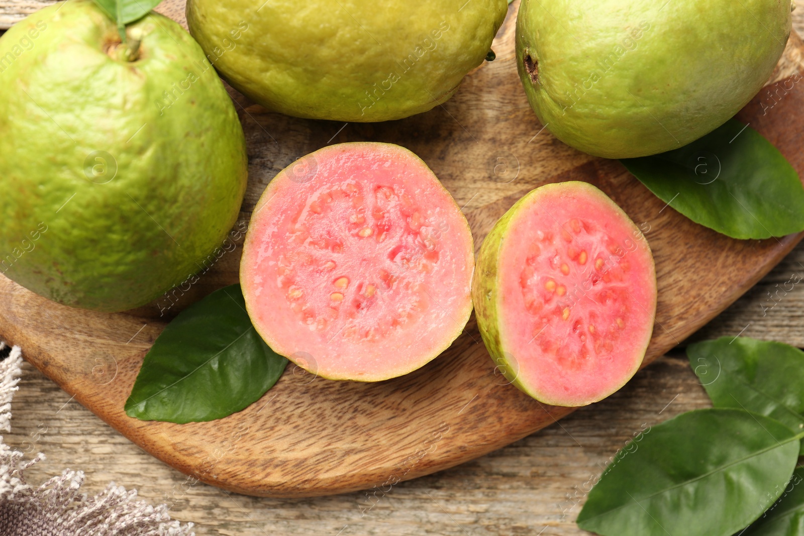 Photo of Fresh whole and cut guava fruits on wooden table, flat lay