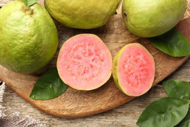 Fresh whole and cut guava fruits on wooden table, flat lay