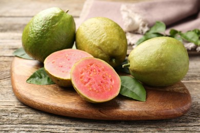 Photo of Fresh whole and cut guava fruits on wooden table, closeup