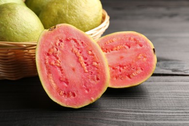 Photo of Fresh whole and cut guava fruits on black wooden table, closeup