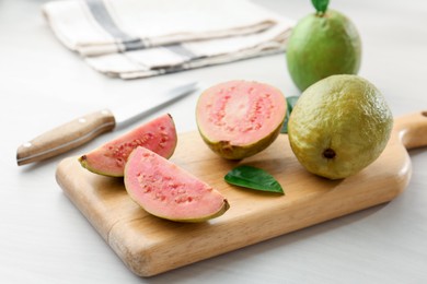 Photo of Fresh whole and cut guava fruits on white wooden table, closeup