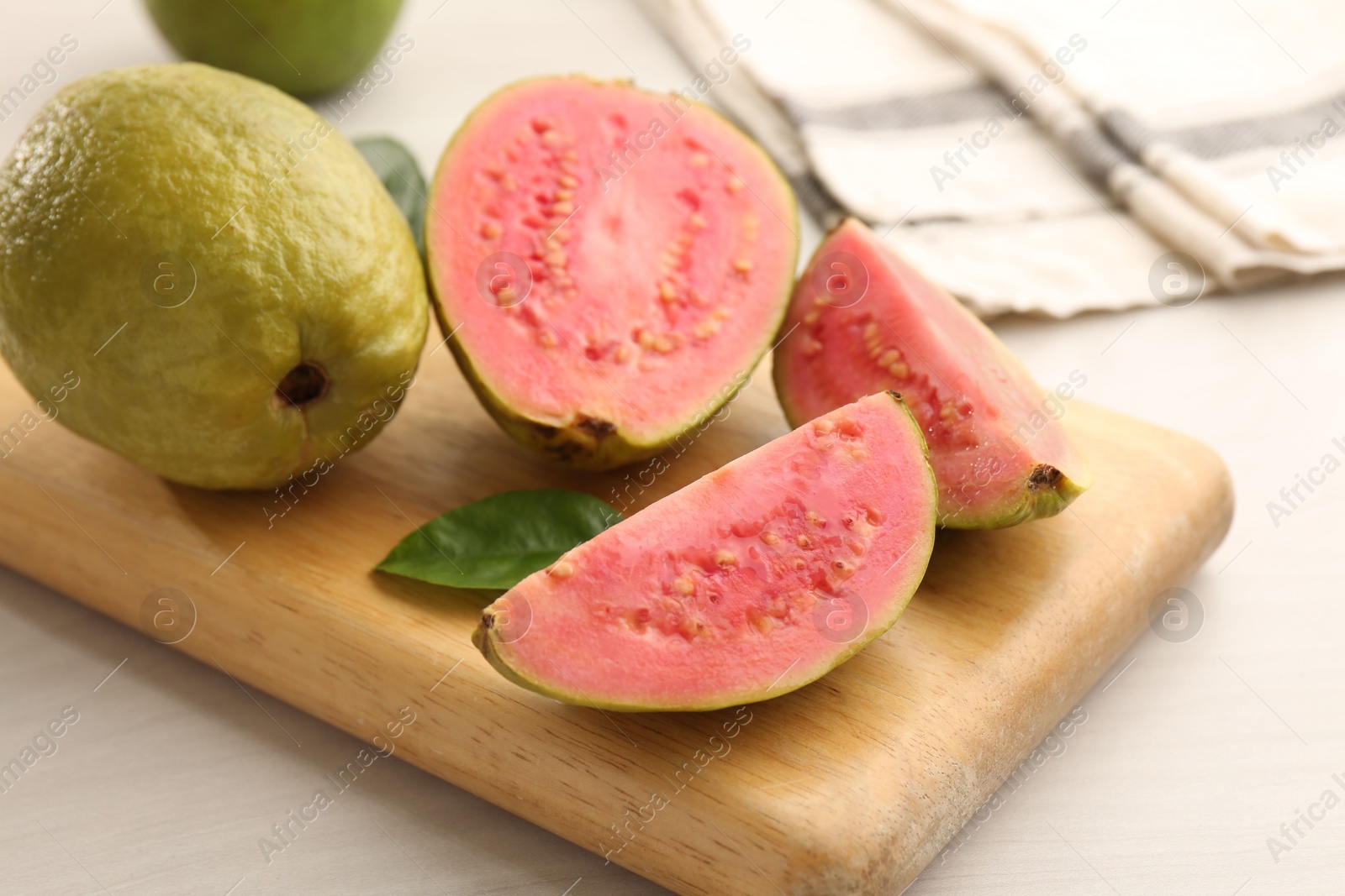 Photo of Fresh whole and cut guava fruits on white wooden table, closeup