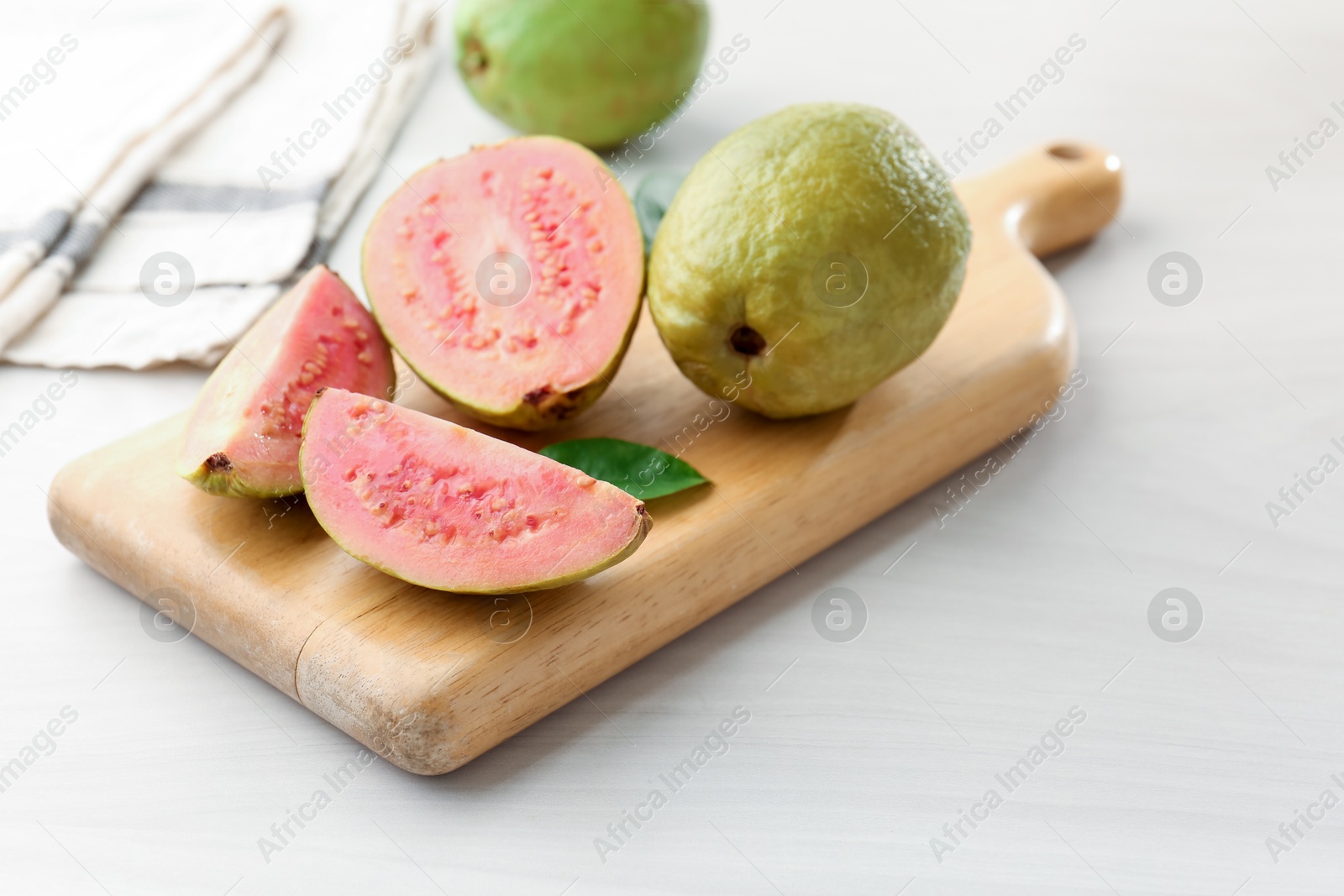 Photo of Fresh whole and cut guava fruits on white wooden table, closeup