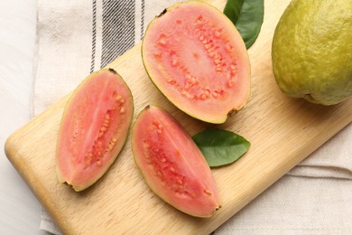 Photo of Fresh whole and cut guava fruits on white wooden table, top view