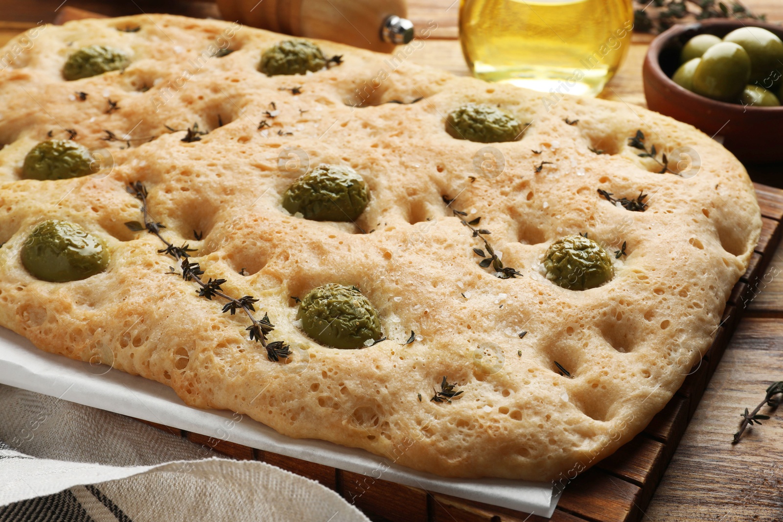 Delicious focaccia bread with olives, salt and thyme on wooden table, closeup Photo of Delicious focaccia bread with olives, salt and thyme on wooden table, closeup