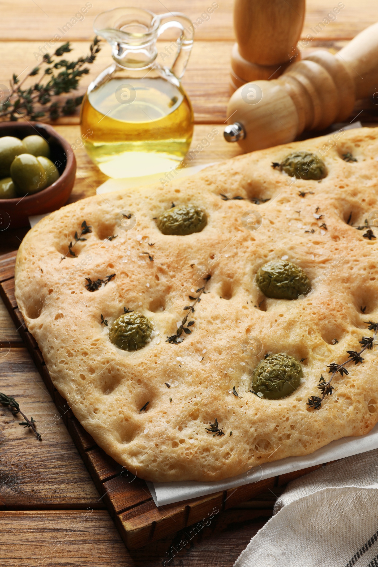Delicious focaccia bread with olives, salt and thyme on wooden table, closeup Photo of Delicious focaccia bread with olives, salt and thyme on wooden table, closeup