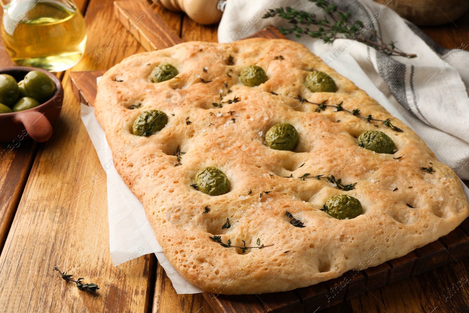 Delicious focaccia bread with olives, salt and thyme on wooden table, closeup Photo of Delicious focaccia bread with olives, salt and thyme on wooden table, closeup