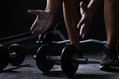 Photo of Man clapping hands with talcum powder before training with barbells on black background, closeup