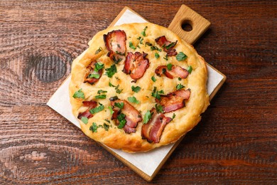 Photo of Delicious focaccia bread with bacon and parsley on wooden table, top view