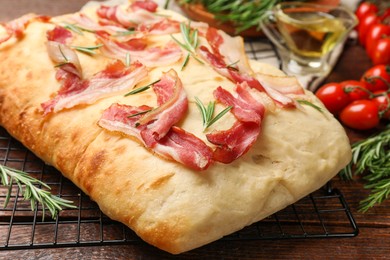 Photo of Delicious focaccia bread with bacon and rosemary on wooden table, closeup