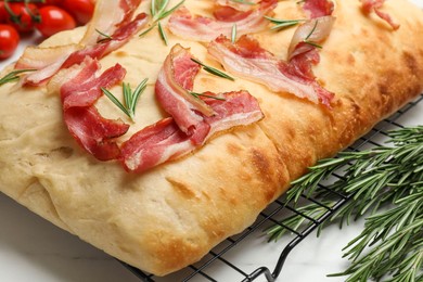 Photo of Delicious focaccia bread with bacon and rosemary on white table, closeup