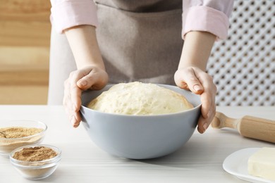 Photo of Making cinnamon rolls. Woman with dough at white wooden table, closeup