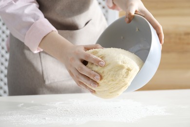 Photo of Making cinnamon rolls. Woman with dough at white table, closeup