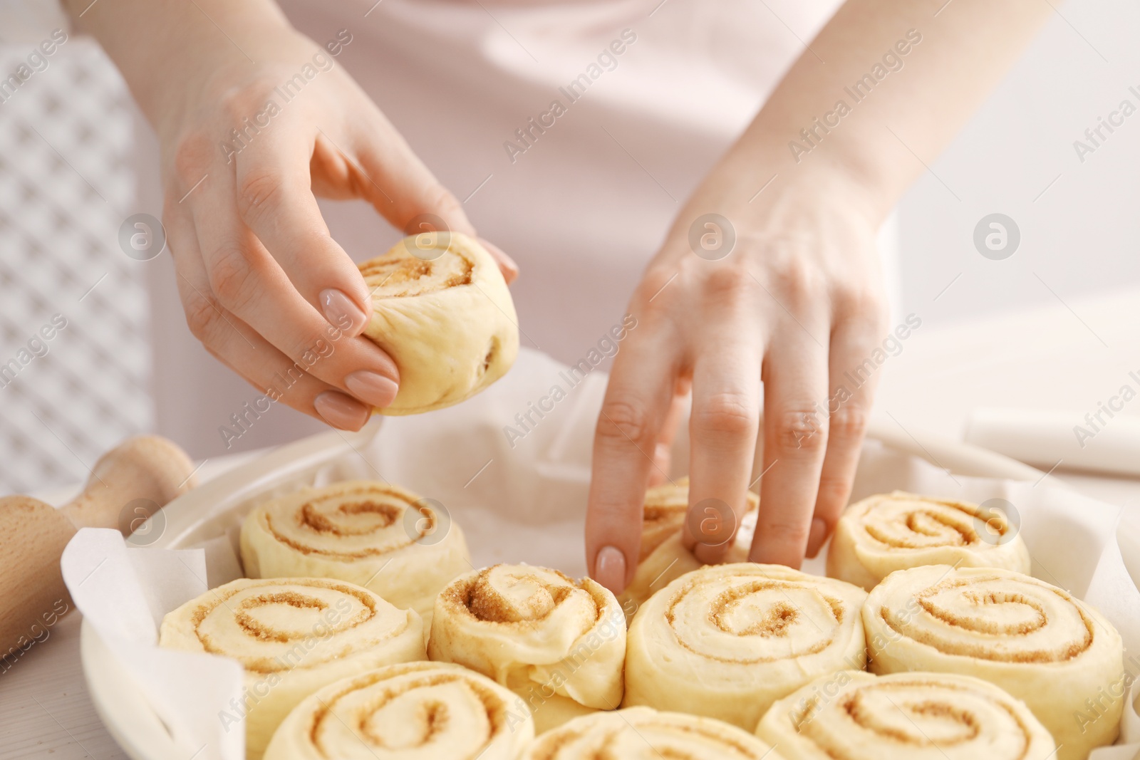 Photo of Woman making cinnamon rolls at table, closeup