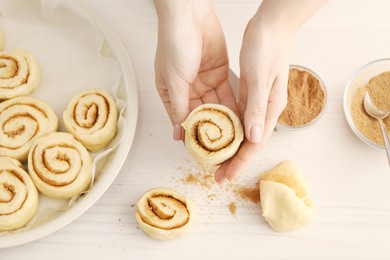 Photo of Woman making cinnamon rolls at white wooden table, top view